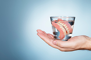 Image of dentures in a glass of water.