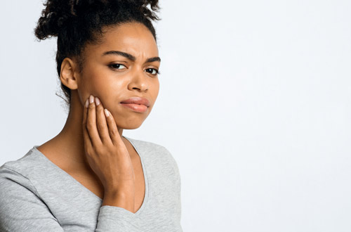 Woman touches her face, where the dentist could place the implant.