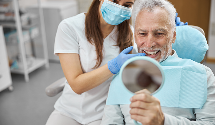 Image of a person looking at teeth after dental implant treatment, at Myers Park Dental Partners in Charlotte, NC.