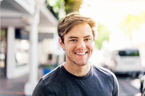 A young man smiling outside