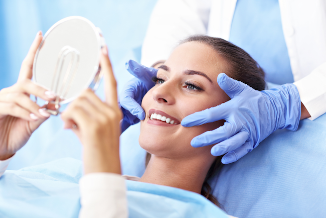 Image of a woman looking at her smile after a dental implant placement, at Myers Park Dental Partners in Charlotte, NC.